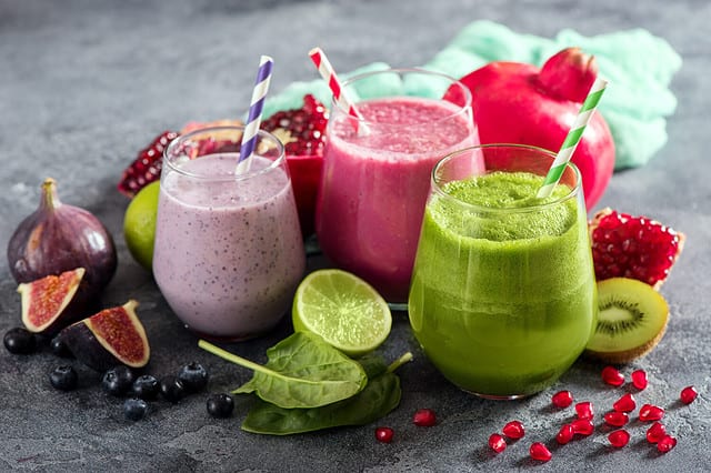 Colorful smoothie, healthy detox vitamin diet or vegan food concept, fresh vitamins, breakfast drink with spinach, pomegranate, figs and blueberries protein shake. Ways to make your hair grow