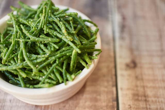 Fresh samphire in a white bowl on an old wooden worktop