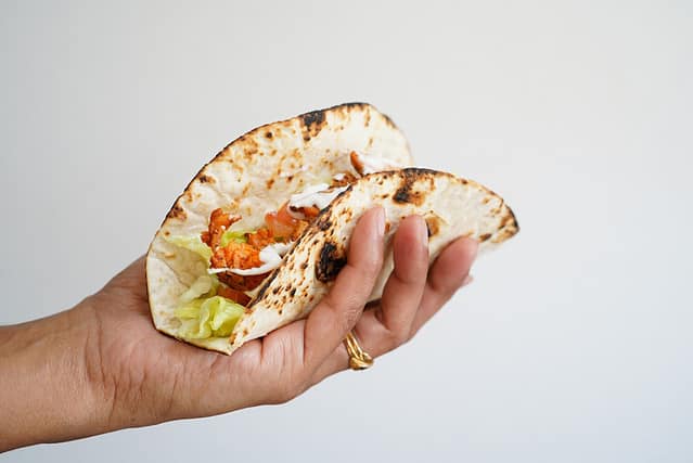 Female hand holding Soft fish tacos isolated on white, selective focus