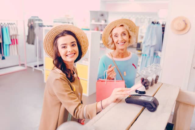 New methods of payment. Smiling woman paying for clothes with a smartphone