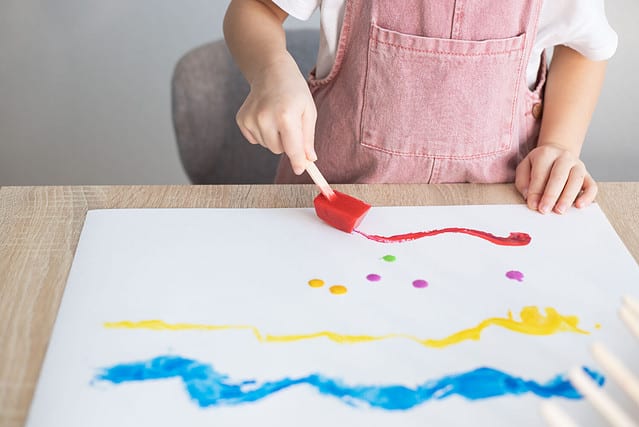 Child painting with colour ice cubes. Creative activities for toddlers. DIY, homemade paints.