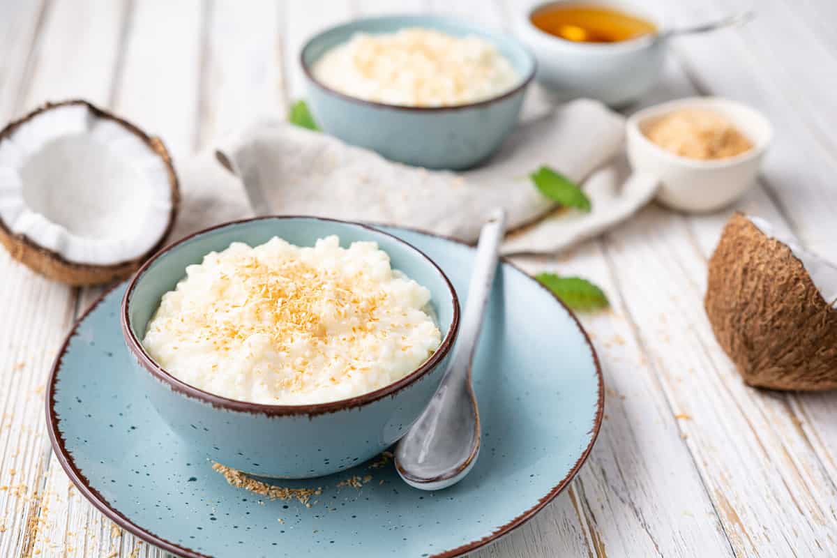 Sweet and creamy coconut rice pudding with honey, topped with grated and toasted coconut in a ceramic bowl