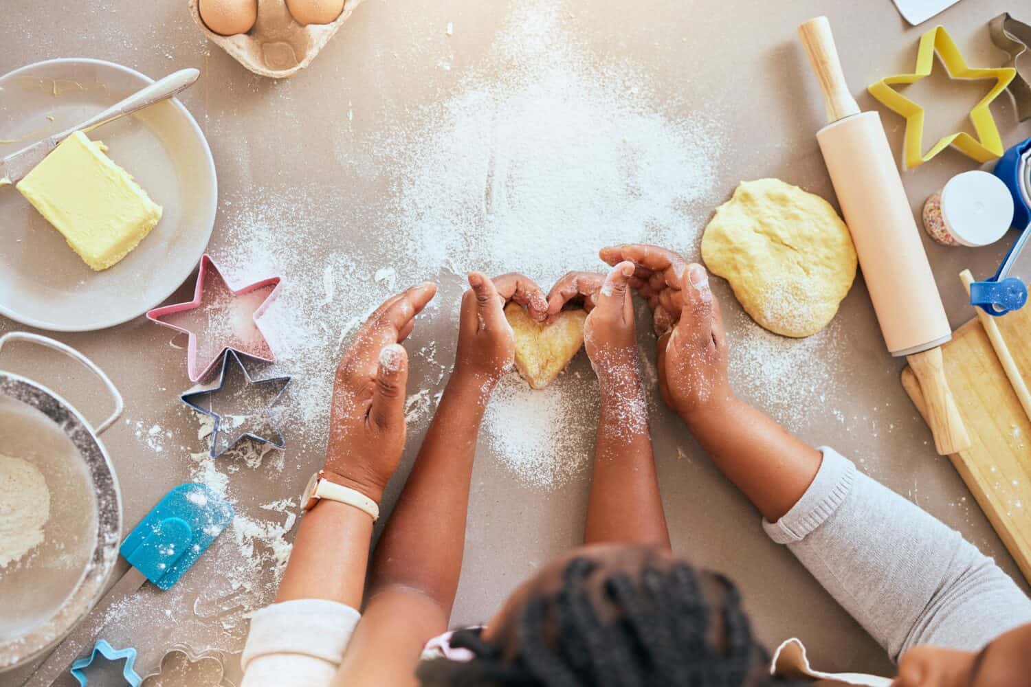 Black woman, child hands or kitchen baking of heart shape pastry, house cookies or dessert biscuit scone in family home. Top view, mother or girl cooking food in help, support or learning cake recipe
