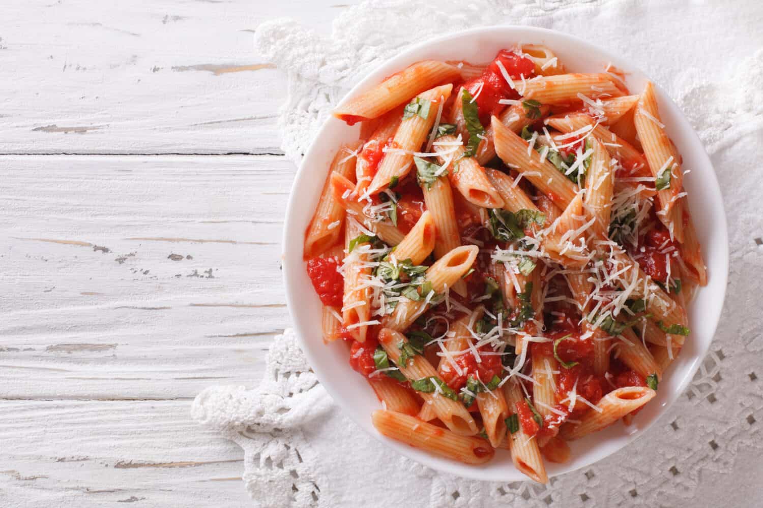 Arrabiata pasta penne with Parmesan cheese on a plate. horizontal top view