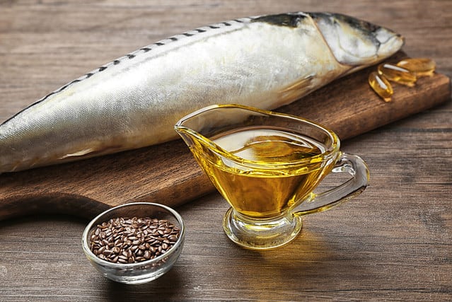 Fish oil with flax grain and fish on wooden background