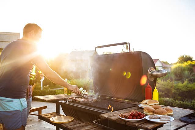 Young men roasting barbecue on grill in cottage countryside.